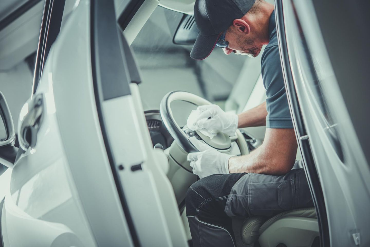 mężczyzna czyści kierownice w samochodzie klienta - detailing wnętrza lubin